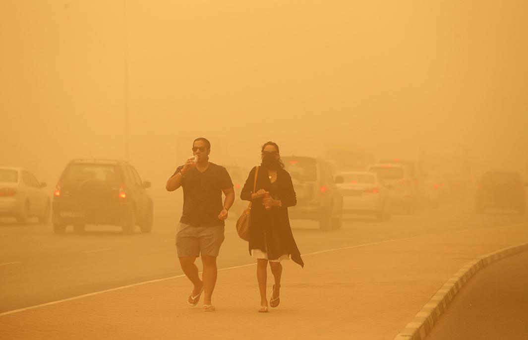 A woman walks with her face covered during a sand storm in Dubai